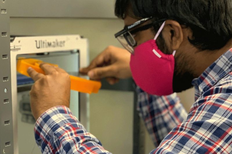 Student removing a completed 3D printed mask from a printer